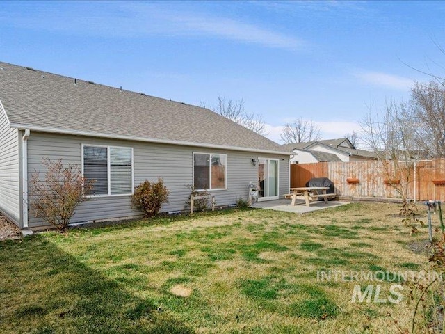 rear view of house with a yard, a patio, roof with shingles, and fence