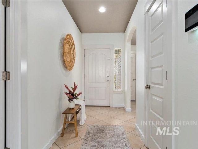 interior space featuring light tile patterned floors, baseboards, arched walkways, and recessed lighting