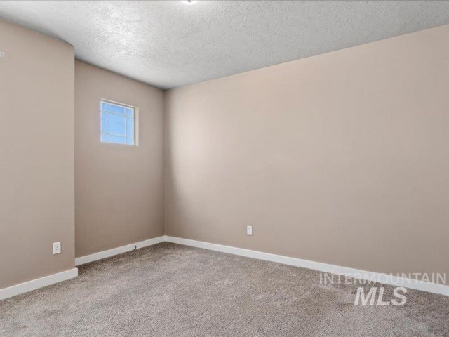 empty room featuring baseboards, carpet, and a textured ceiling