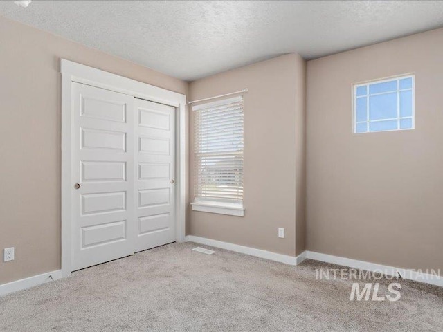 unfurnished bedroom with a closet, a textured ceiling, baseboards, and carpet floors