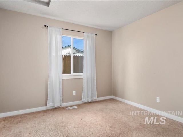 spare room with baseboards, carpet floors, and visible vents