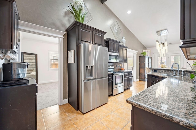 kitchen featuring stainless steel appliances, dark brown cabinets, a healthy amount of sunlight, light tile patterned floors, and a sink