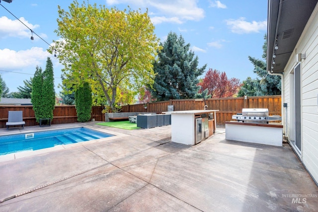 view of pool featuring a fenced backyard, a patio, exterior kitchen, and area for grilling