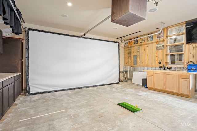 home theater featuring a garage, electric panel, and unfinished concrete floors