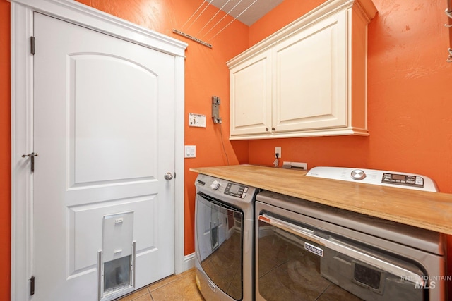 laundry area featuring light tile patterned flooring, washer and dryer, and cabinet space