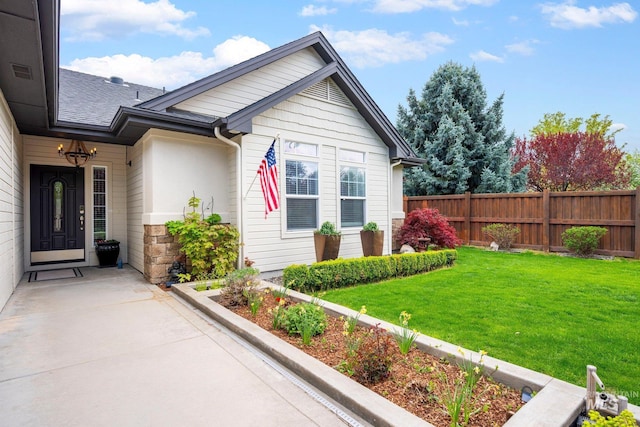 view of side of property with fence, stone siding, and a yard