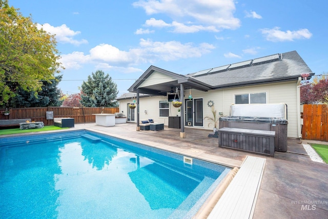 back of property featuring a fenced in pool, a fenced backyard, solar panels, a patio area, and a hot tub