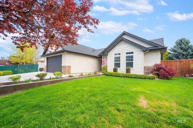 view of front of home with driveway, stone siding, fence, a garage, and a front yard