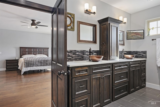 ensuite bathroom featuring a sink, tasteful backsplash, and wood finished floors