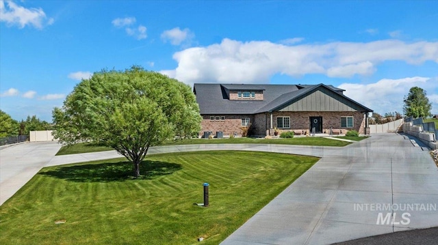 craftsman-style house with board and batten siding, concrete driveway, a front yard, and fence