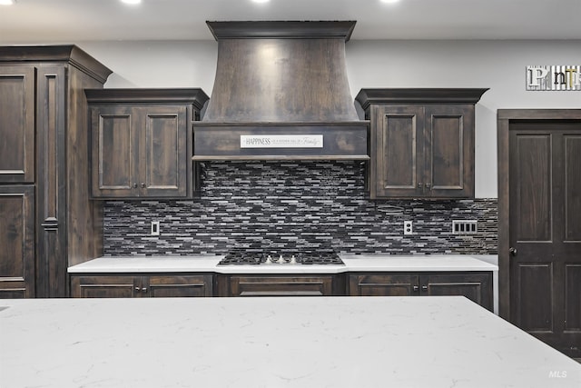 kitchen featuring decorative backsplash, dark brown cabinetry, custom range hood, and gas stovetop