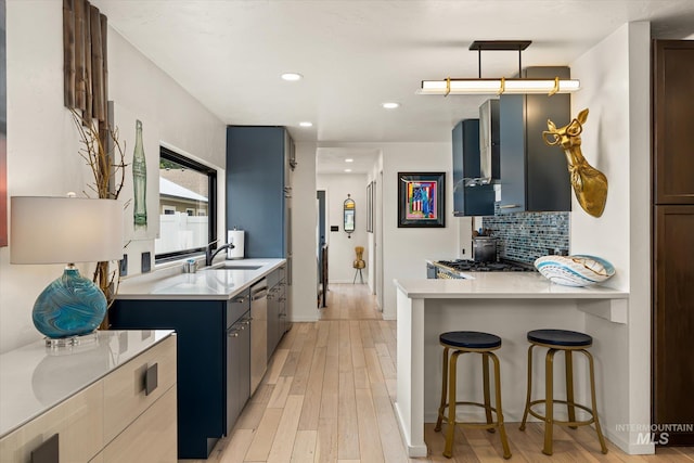 2402 Columbus, Boise, ID 83705 - kitchen with light countertops, a sink, a kitchen bar, tasteful backsplash, and light wood-type flooring