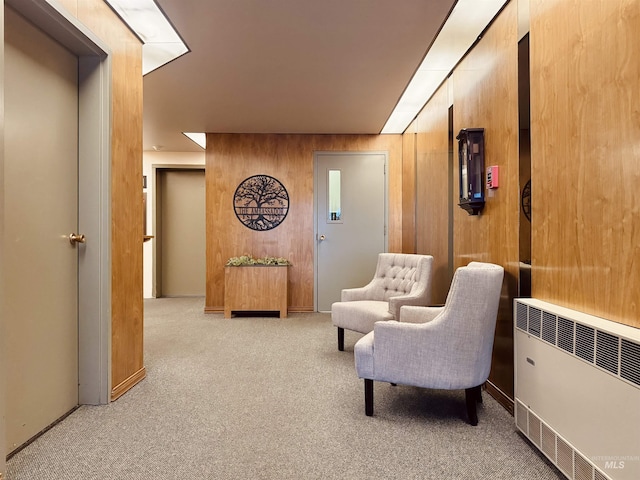 sitting room with wood walls, carpet, and radiator