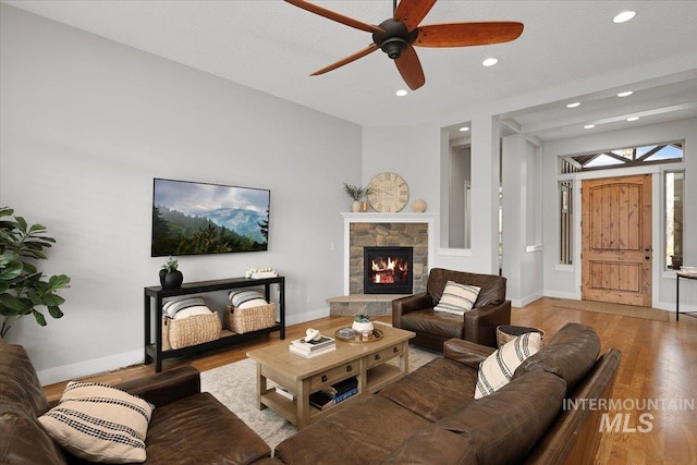 living area featuring ceiling fan, recessed lighting, a fireplace, wood finished floors, and baseboards