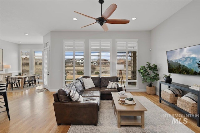 living room featuring baseboards, light wood-type flooring, a ceiling fan, and recessed lighting