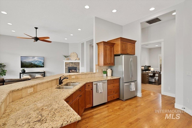 kitchen with appliances with stainless steel finishes, open floor plan, visible vents, and a sink