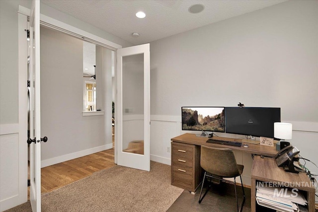 carpeted office space featuring baseboards, a textured ceiling, and french doors