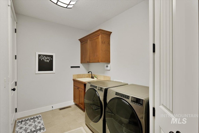 laundry area featuring a sink, visible vents, baseboards, cabinet space, and washer and clothes dryer