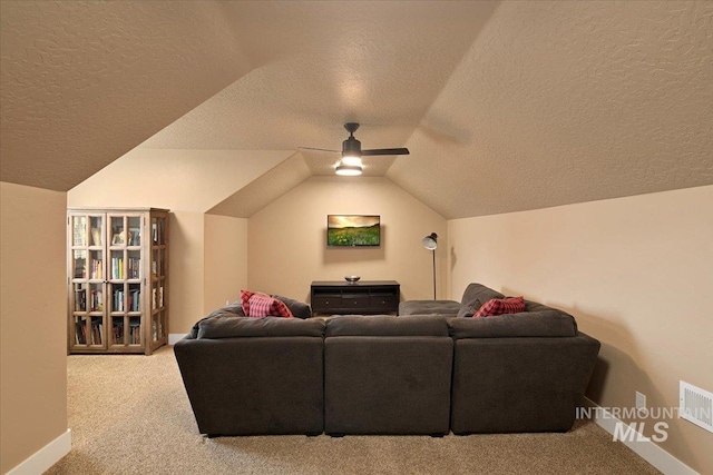 living area with lofted ceiling, ceiling fan, a textured ceiling, and carpet flooring