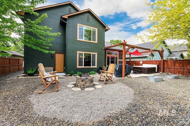 rear view of property featuring a patio, an outdoor fire pit, a fenced backyard, and a hot tub