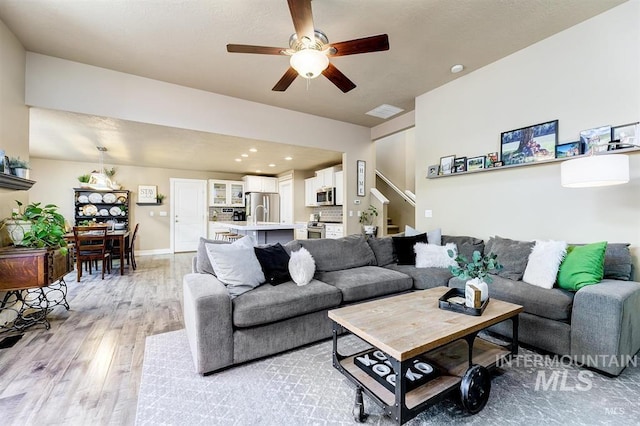 living room with light wood-type flooring, visible vents, a ceiling fan, recessed lighting, and stairs