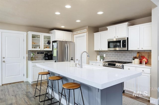 kitchen featuring a breakfast bar area, white cabinetry, stainless steel appliances, and a sink