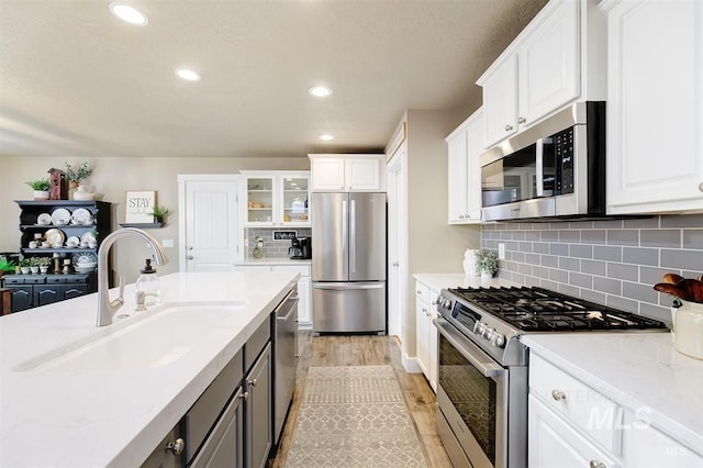 kitchen featuring a sink, stainless steel appliances, light wood-style floors, and white cabinets