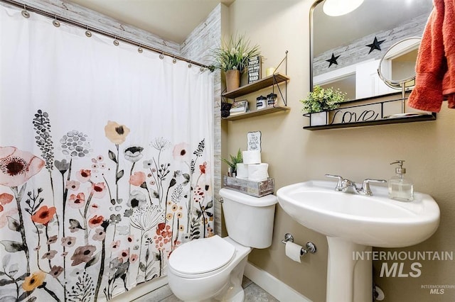 bathroom with curtained shower, toilet, and baseboards