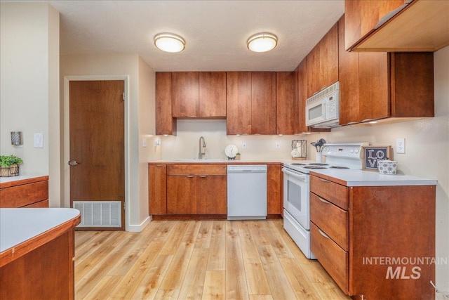 1134 N Camelot Dr, Boise, ID 83704 - kitchen featuring white appliances, brown cabinets, light wood-style floors, and light countertops
