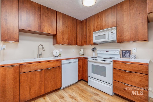 1134 N Camelot Dr, Boise, ID 83704 - kitchen with white appliances, light countertops, light wood-type flooring, and brown cabinets
