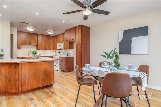 1134 N Camelot Dr, Boise, ID 83704 - kitchen featuring white appliances, brown cabinetry, light countertops, recessed lighting, and a peninsula