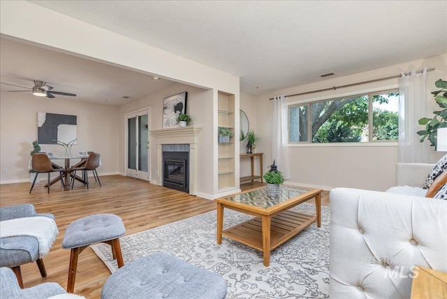 1134 N Camelot Dr, Boise, ID 83704 - living room with light wood-style floors, a glass covered fireplace, a ceiling fan, and built in features