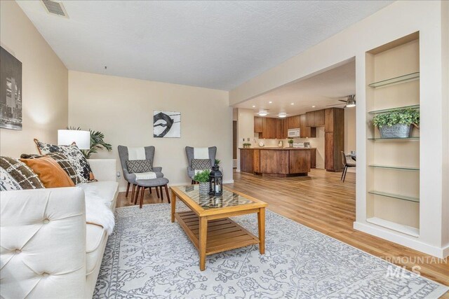 1134 N Camelot Dr, Boise, ID 83704 - living area with light wood-style floors, ceiling fan, and built in shelves