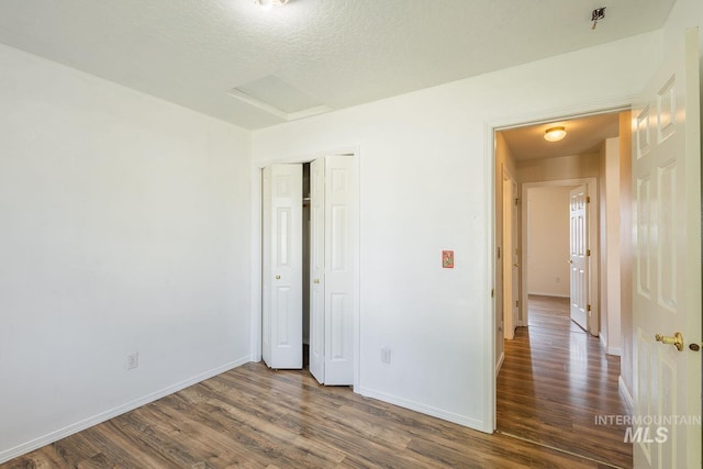 4709 Pioneer Ave, Caldwell, ID 83607 - unfurnished bedroom featuring attic access, dark wood-type flooring, baseboards, a closet, and a textured ceiling
