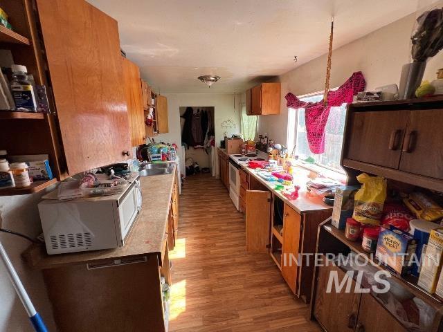 1495 W 7th, Weiser, ID 83672 - kitchen featuring white appliances, light wood-style floors, brown cabinetry, open shelves, and light countertops