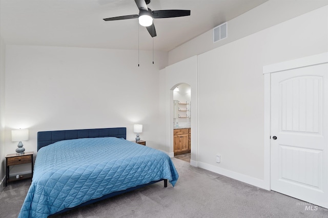 bedroom featuring arched walkways, carpet floors, baseboards, ensuite bath, and visible vents