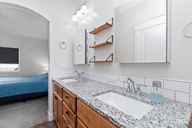 ensuite bathroom with decorative backsplash, a sink, and double vanity