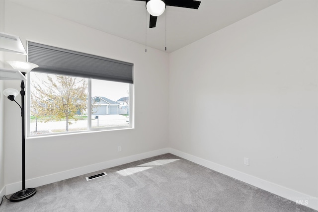 carpeted empty room with baseboards, a ceiling fan, and visible vents