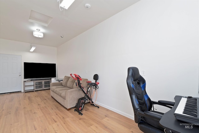 office space featuring attic access, light wood finished floors, and baseboards