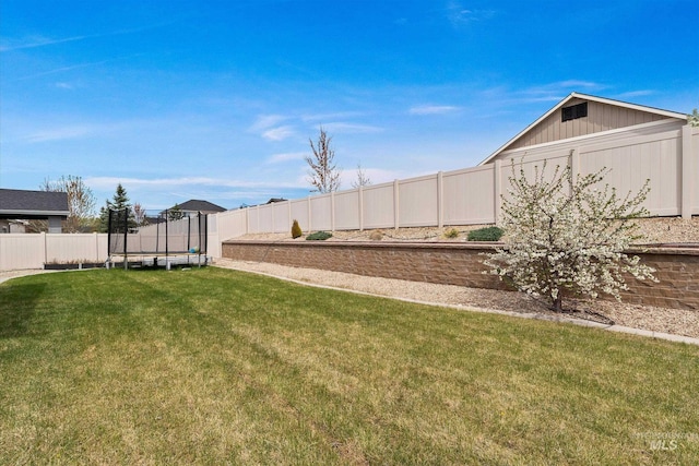 view of yard with a trampoline and a fenced backyard