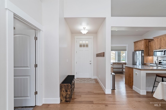 entryway with light wood-type flooring and baseboards