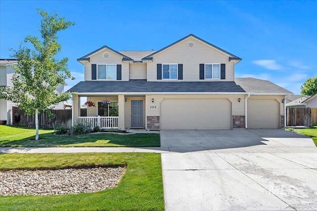 traditional-style home with fence, covered porch, a front lawn, concrete driveway, and stone siding