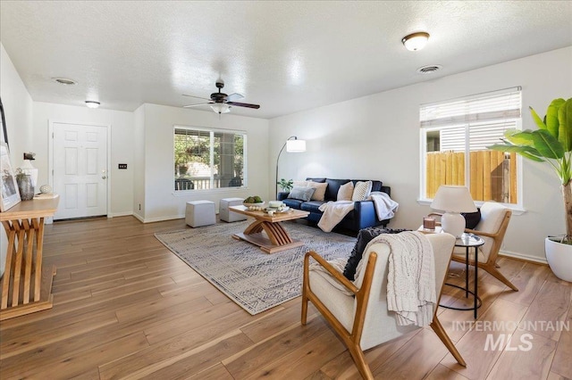 living area featuring light wood-style flooring, visible vents, and a textured ceiling