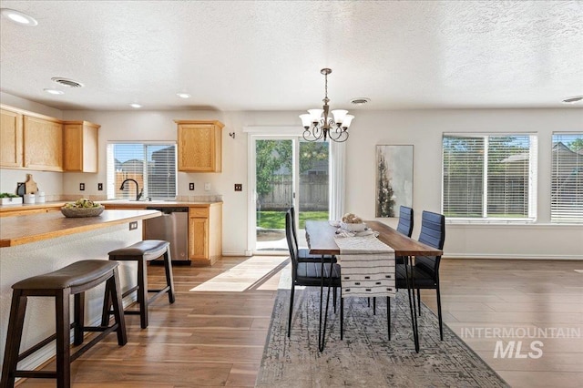 dining room featuring a notable chandelier, a textured ceiling, visible vents, and wood finished floors