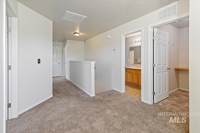 unfurnished room featuring baseboards, light colored carpet, visible vents, and a textured ceiling