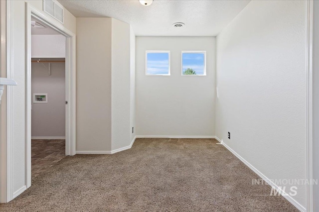 unfurnished room featuring visible vents, baseboards, carpet, and a textured ceiling