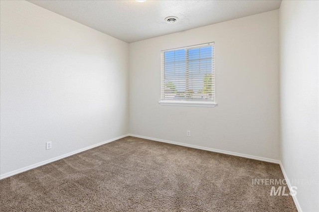 carpeted spare room featuring baseboards, visible vents, and a textured ceiling