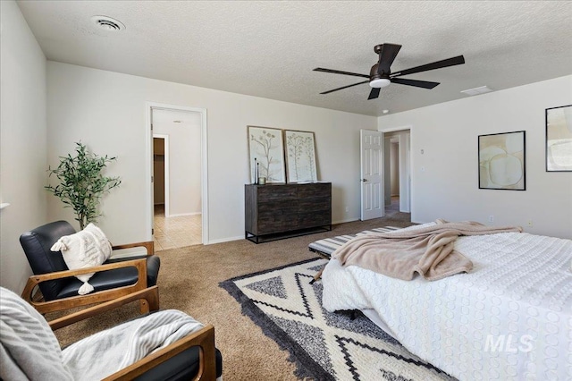 carpeted bedroom with visible vents, a textured ceiling, and a ceiling fan