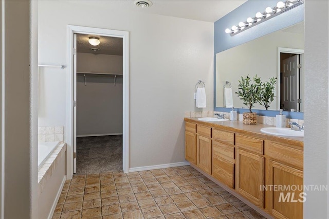 bathroom featuring a walk in closet, double vanity, visible vents, and a sink