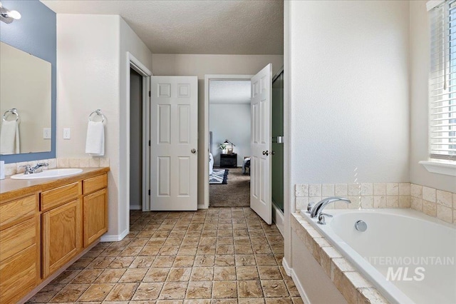 bathroom featuring baseboards, vanity, a garden tub, ensuite bath, and a textured ceiling